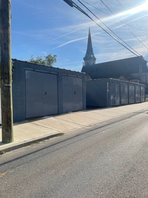 A church with a steeple and a fence on the side of it.